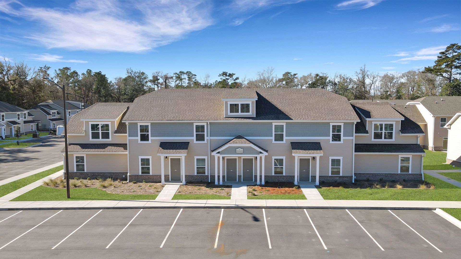 An aerial view of a large apartment building with a parking lot in front of it.