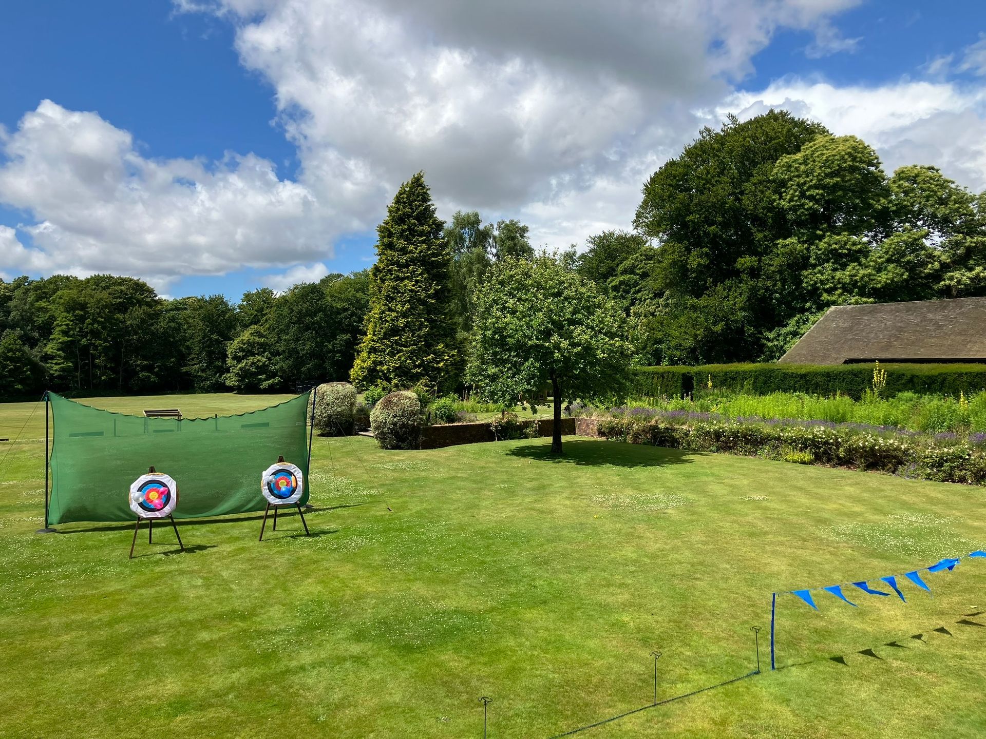 Archery bows and arrows set up in a line on a field with 2 targets in the distance