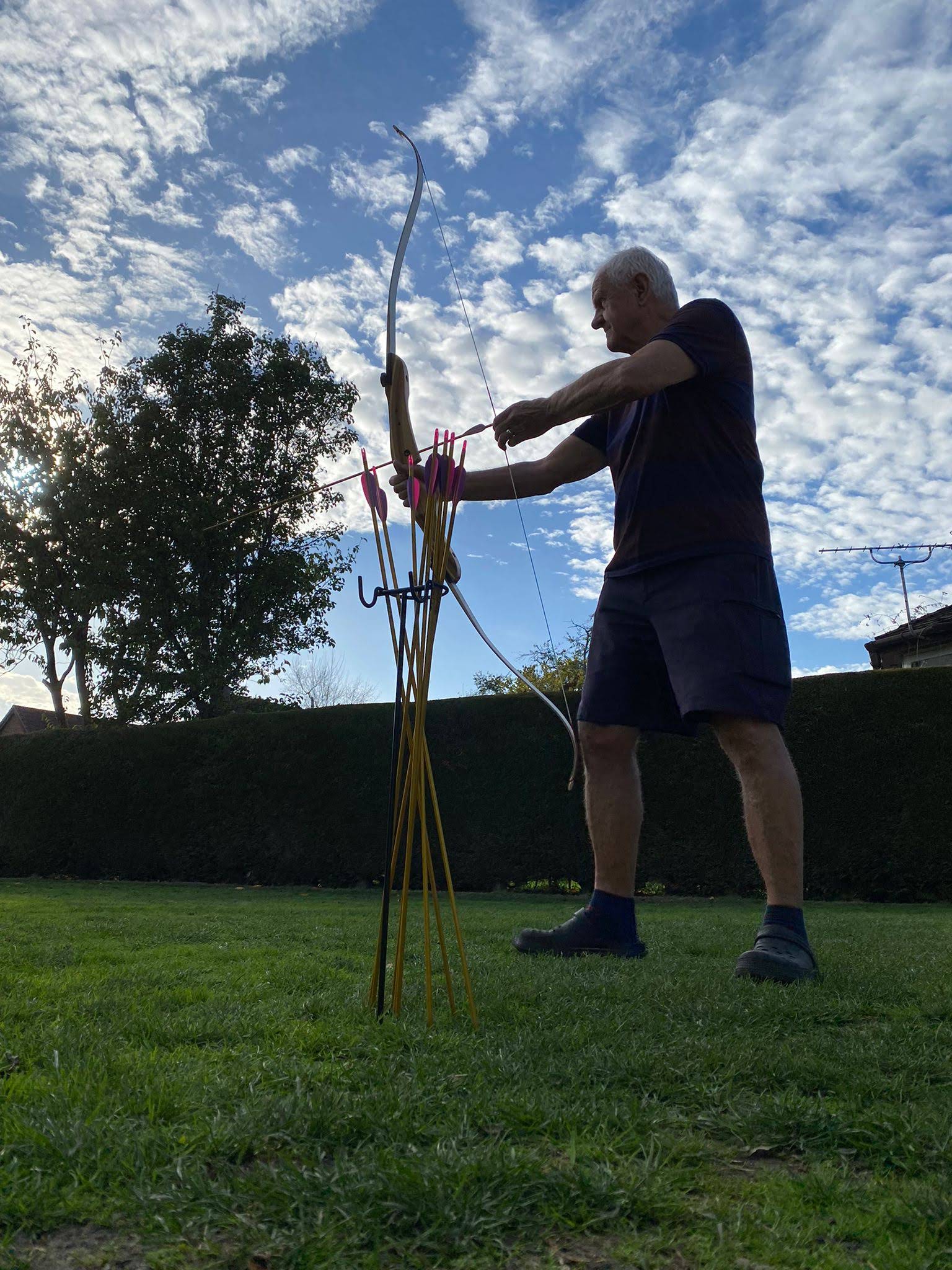 A man about to shoot an arrow for a private event in a garden