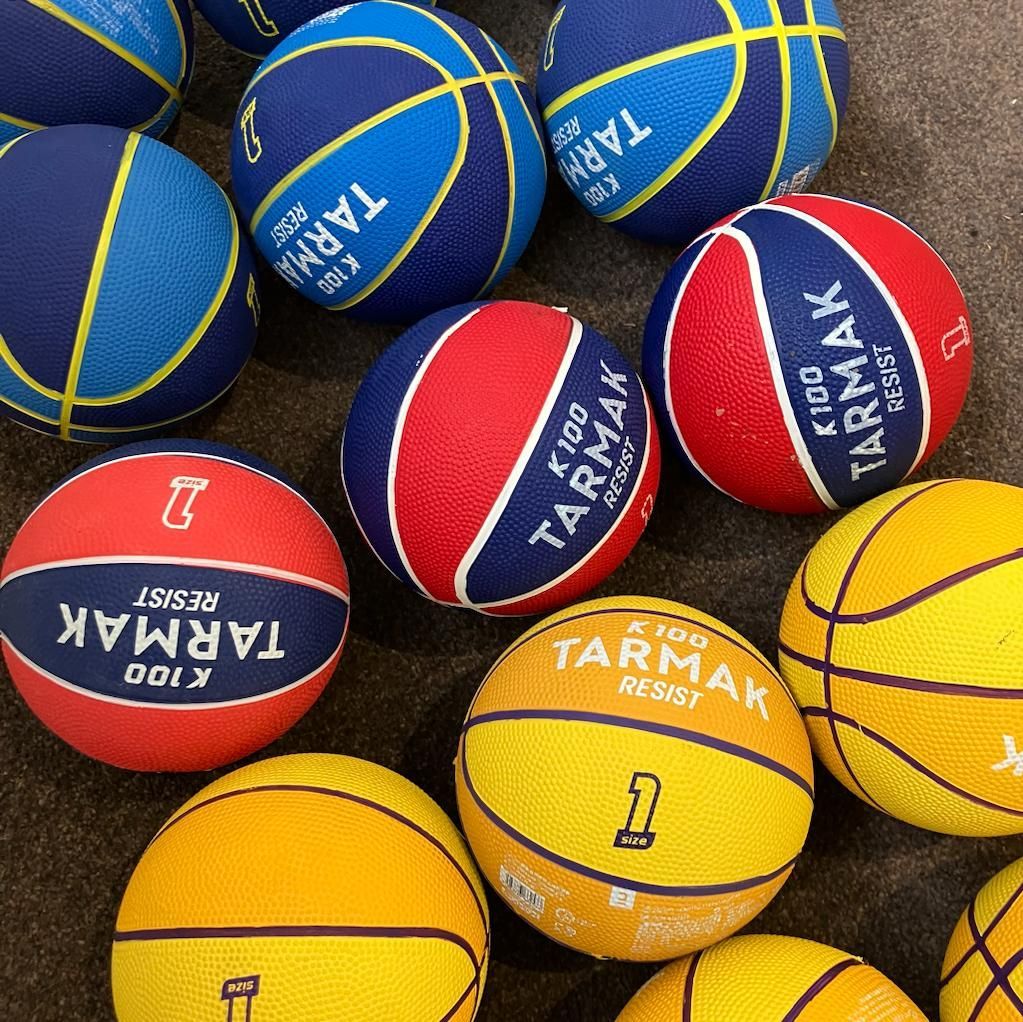 9 mini basketballs, 3 yellow, 3 red and 3 blue all lined up next to each other.