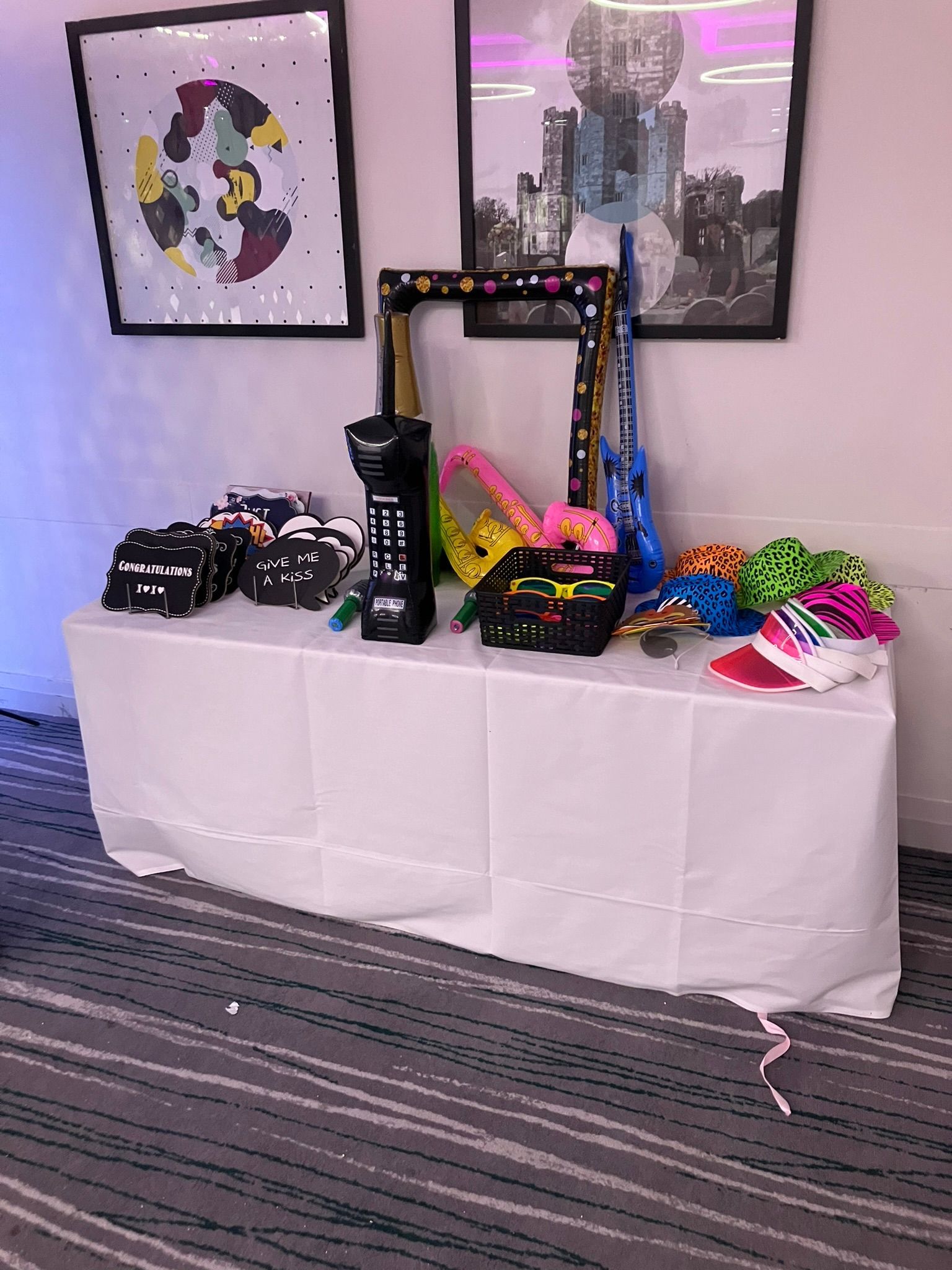 A table with a white table cloth with props for the selfie pod on it.