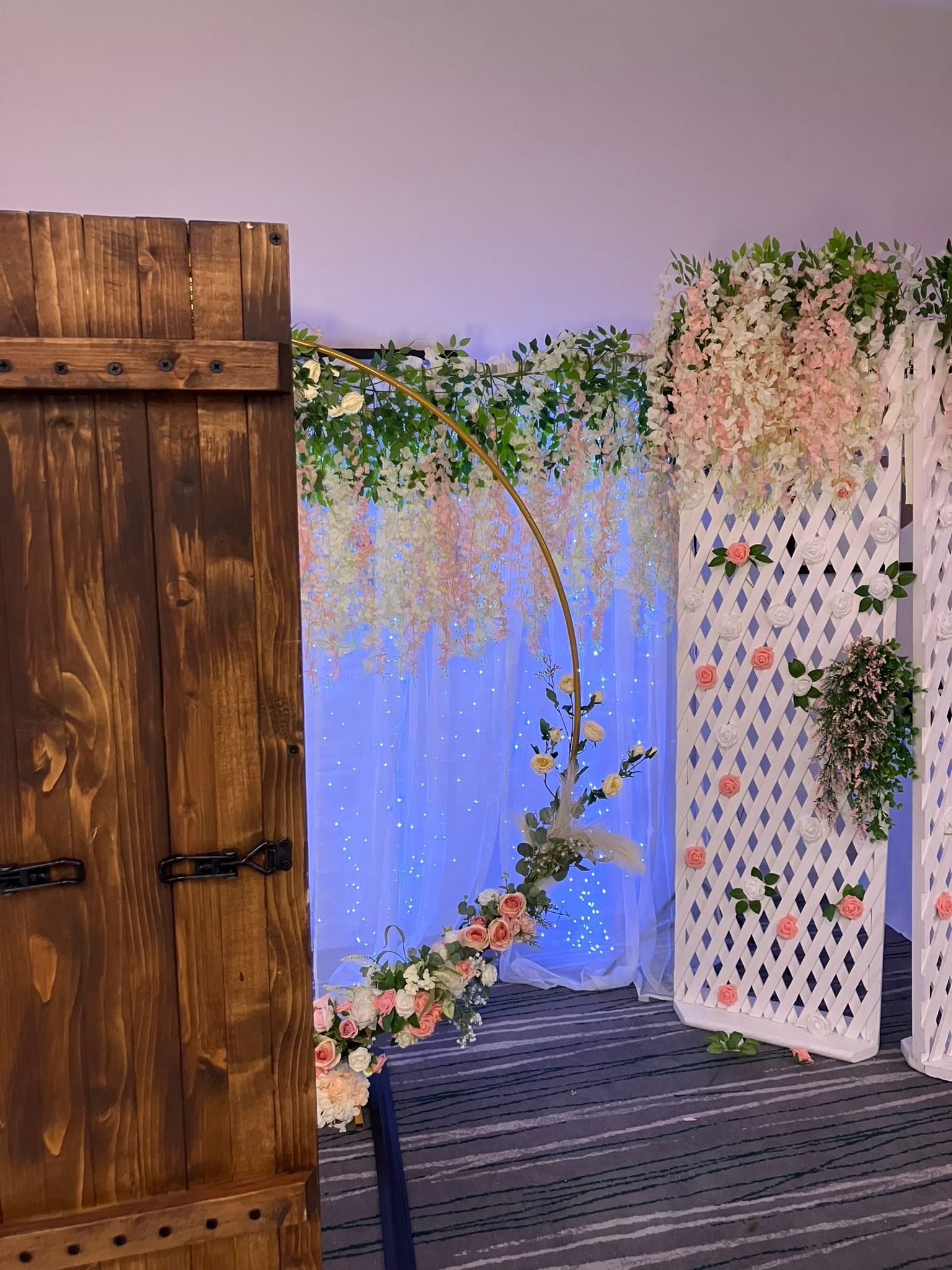 Back view of the selfie pod in front of a flower wall at a wedding.