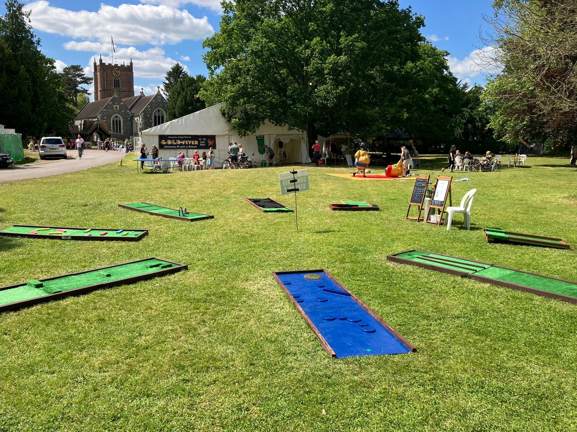 Mini golf set up in a circle on a green field for a community event.