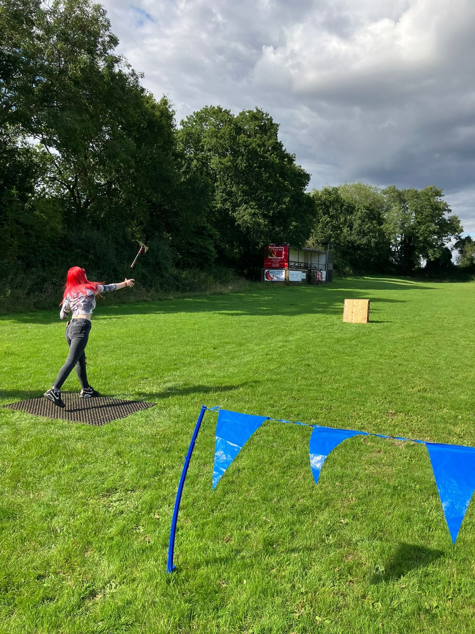 A woman throwing an axe at a target on a green field