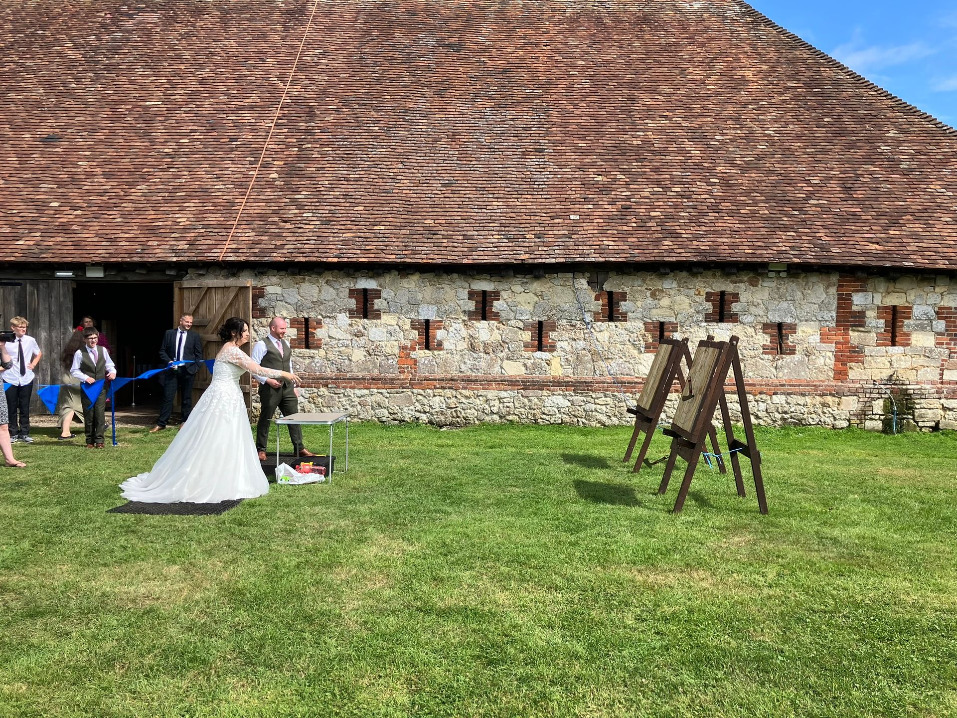 2 wooden axe throwing target on a field with a newly married couple throwing axes