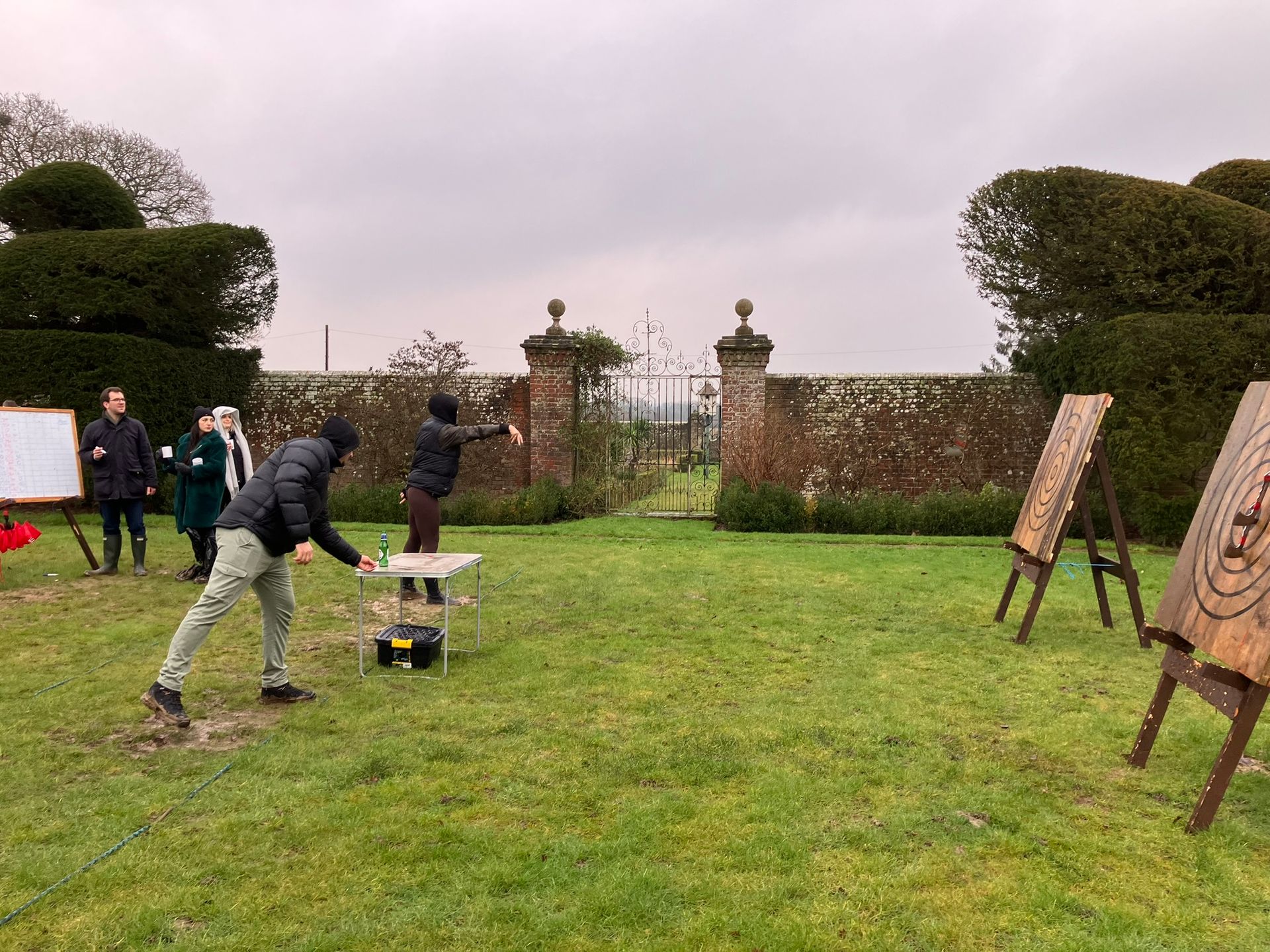 2 wooden axe throwing target on a field with 2 men throwing an axe 