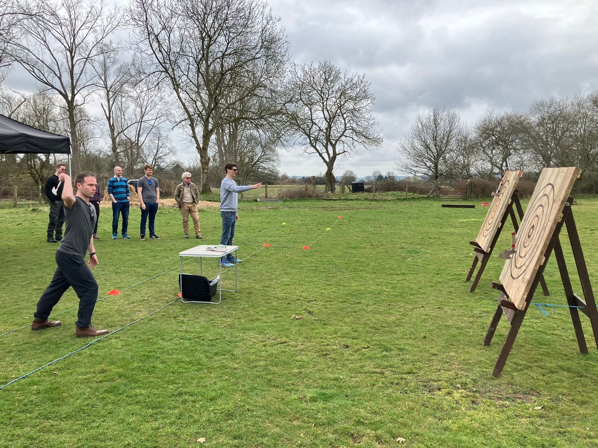 2 wooden axe throwing target on a field with 2 men throwing an axe 