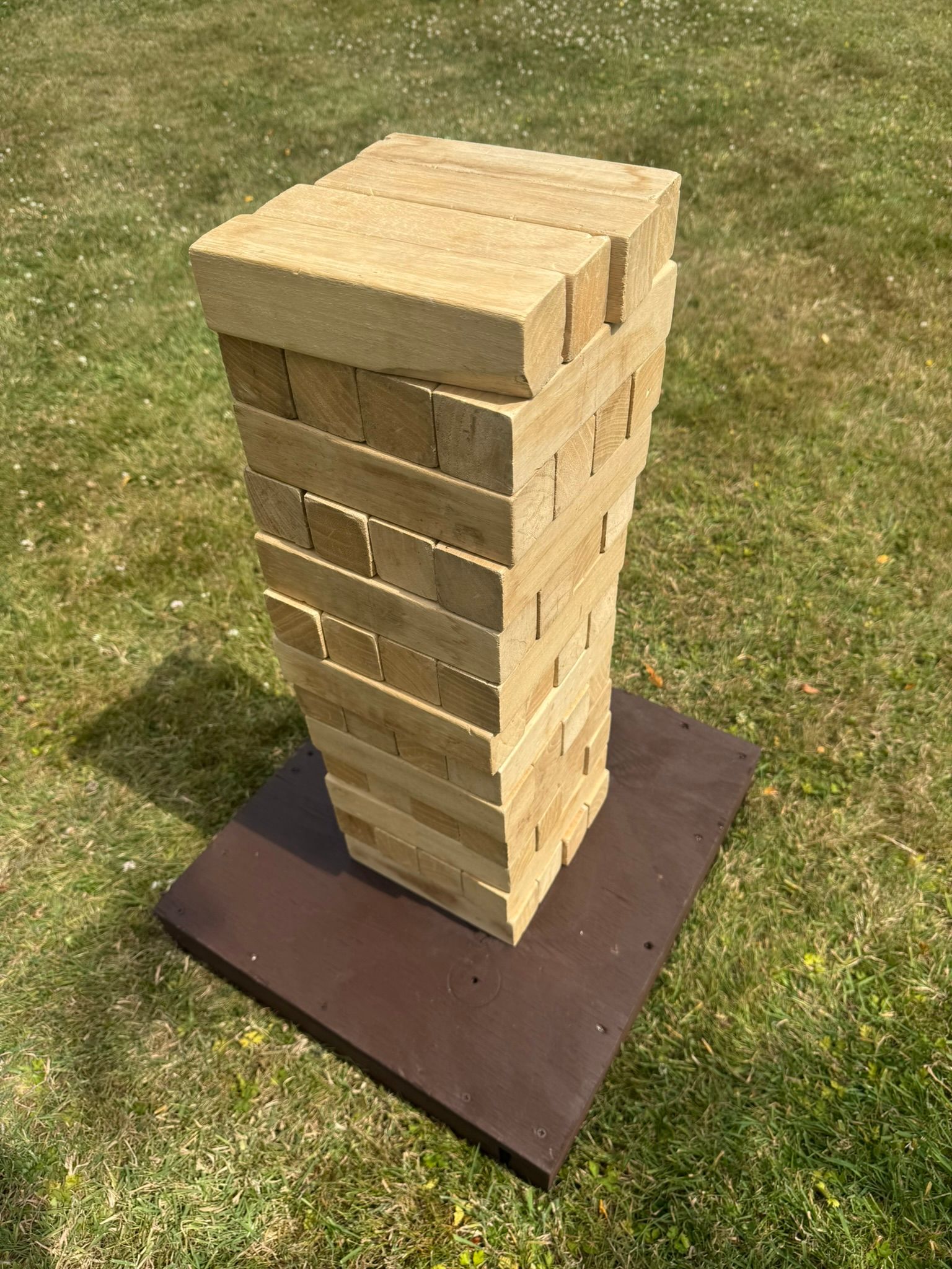 GO Event Hires wooden giant jenga lawn game set up in a tower, on a wooden base.
