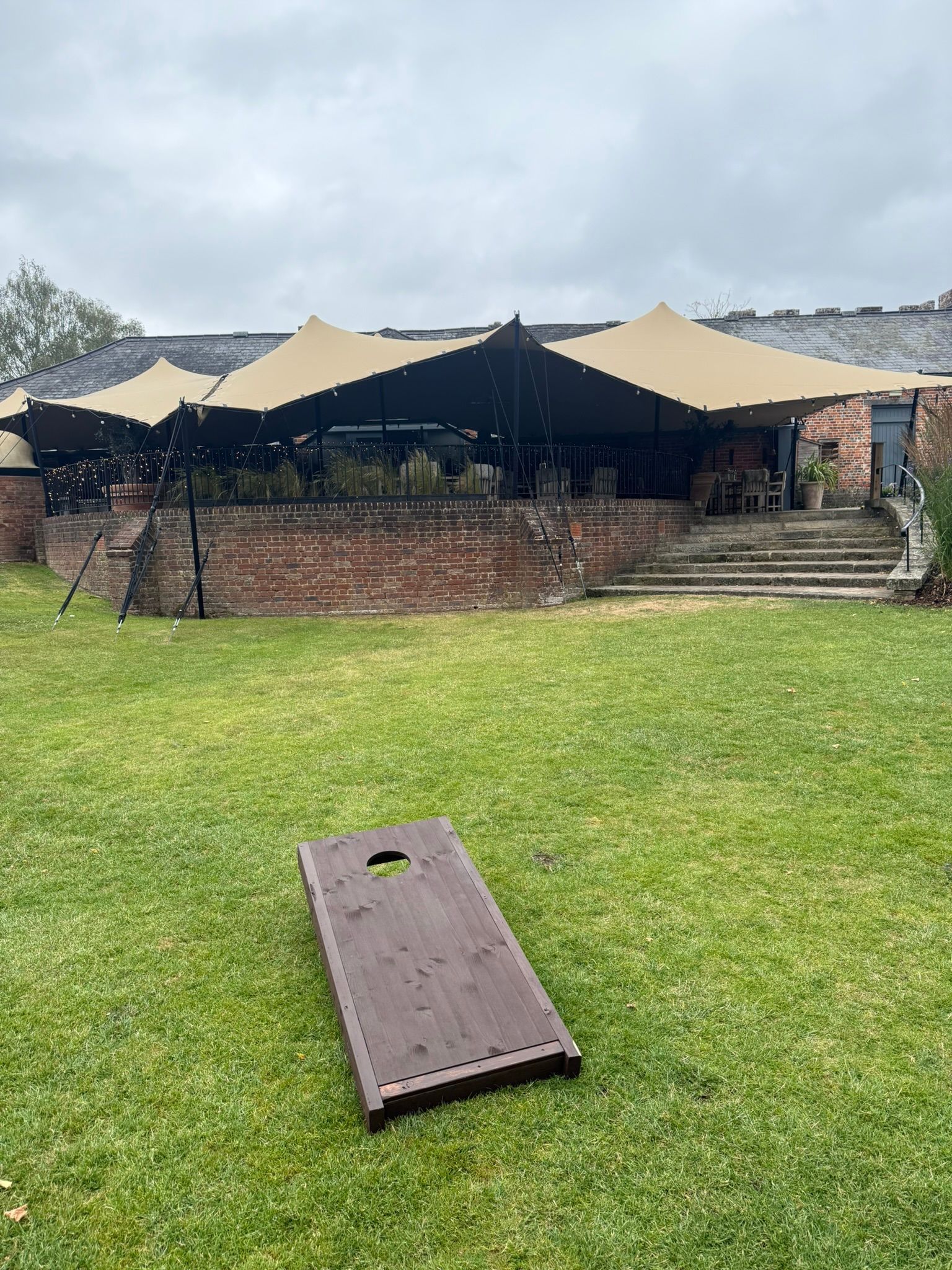 Wooden cornhole board on grass in front of a hotel for a wedding 