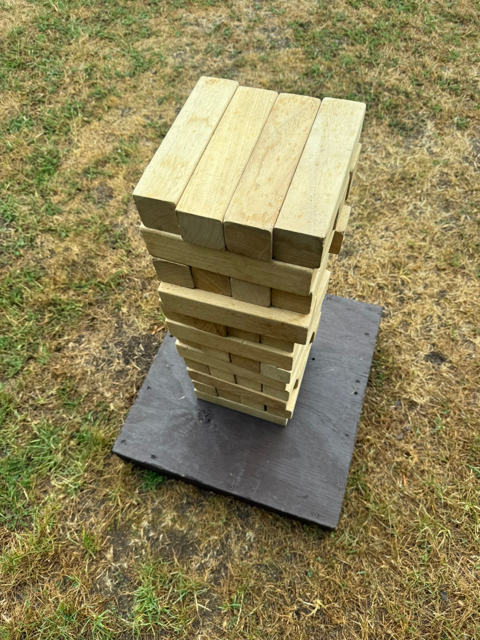 GO Event Hires wooden giant jenga lawn game set up in a tower, on a wooden base.