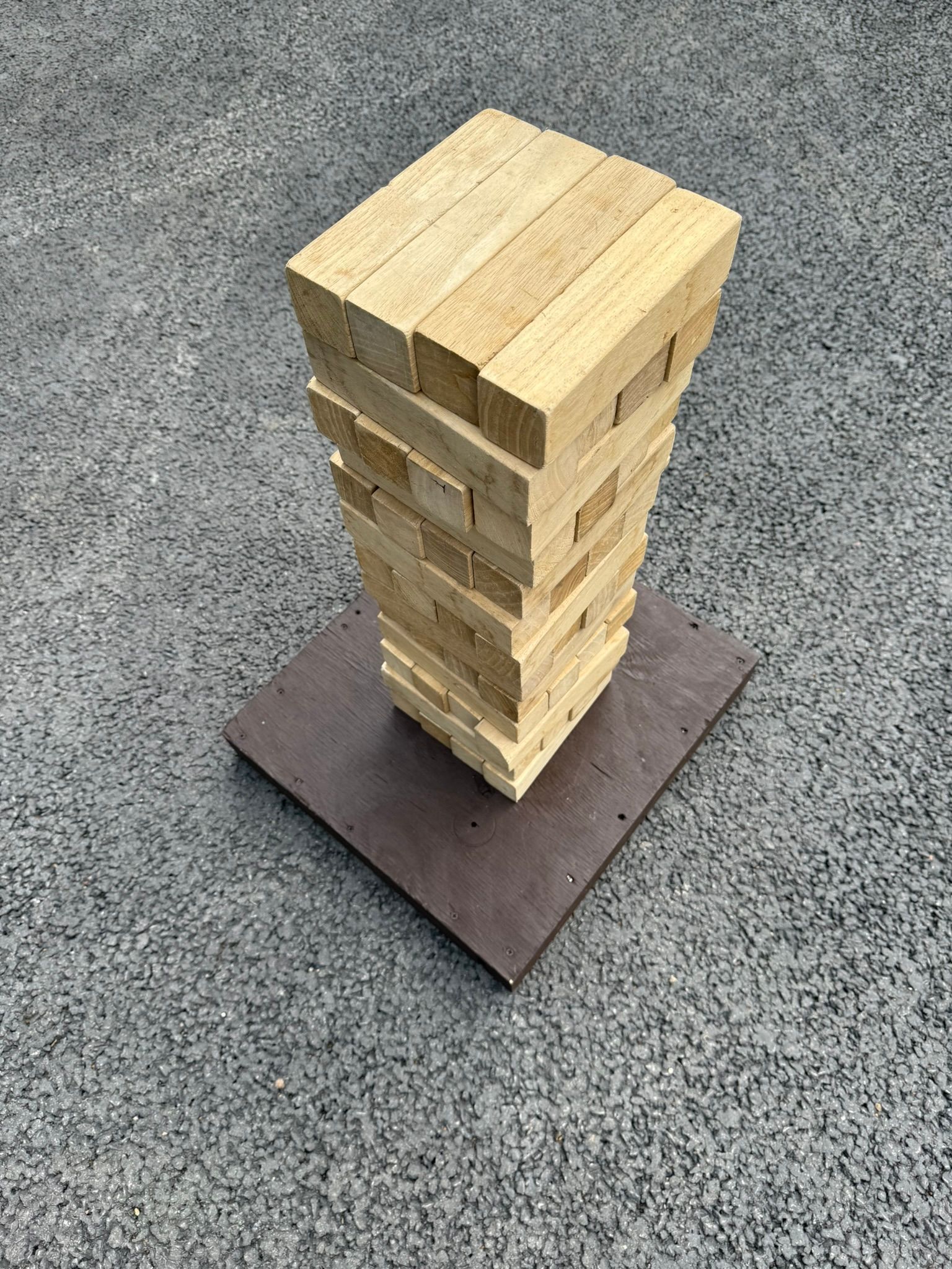 GO Event Hires wooden giant jenga lawn game set up in a tower, on a wooden base.