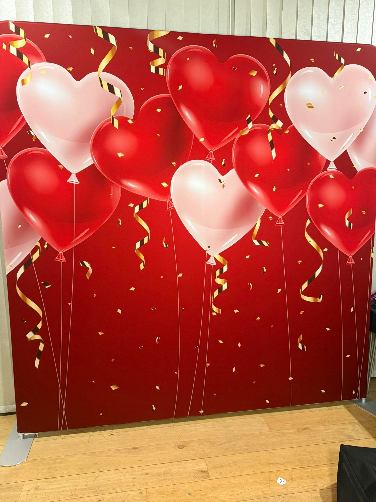 Red background with pink and red balloons in heart shapes in the top half od the backdrop