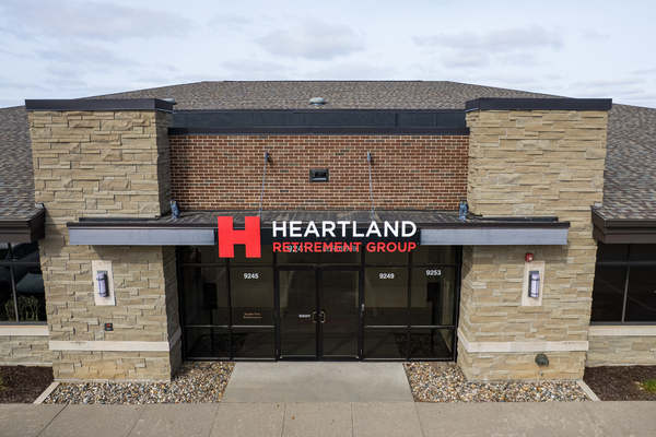 A group of people are walking across a bridge over a river in a park.