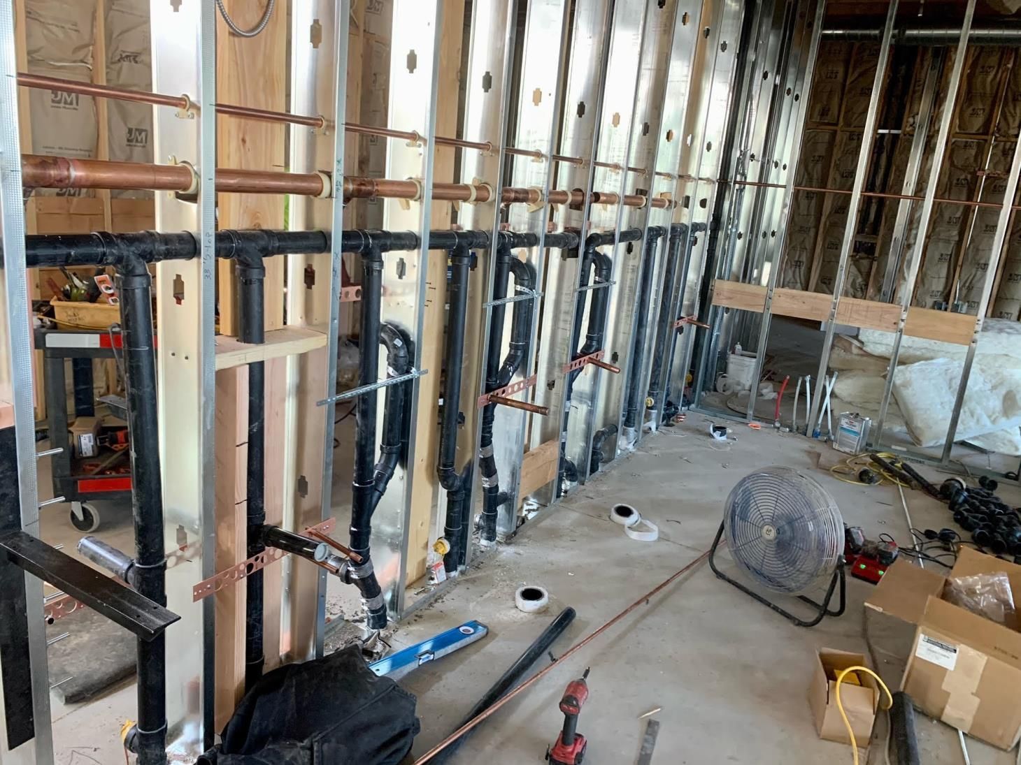 Partially demolished room with exposed wall studs, wiring, tools, and construction debris on the floor