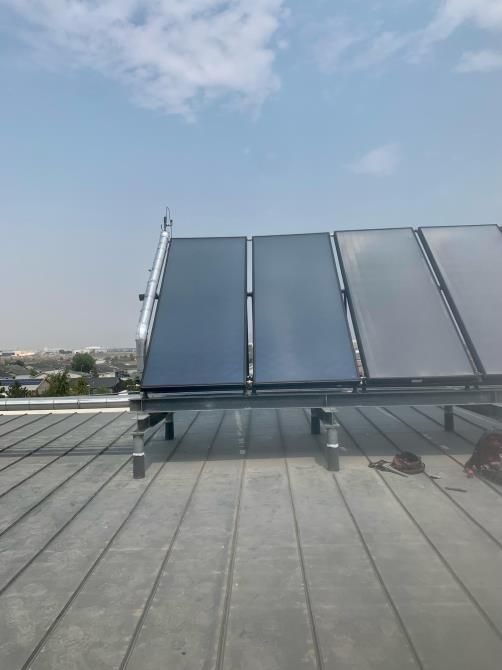 Row of solar thermal panels on a flat rooftop under a clear blue sky
