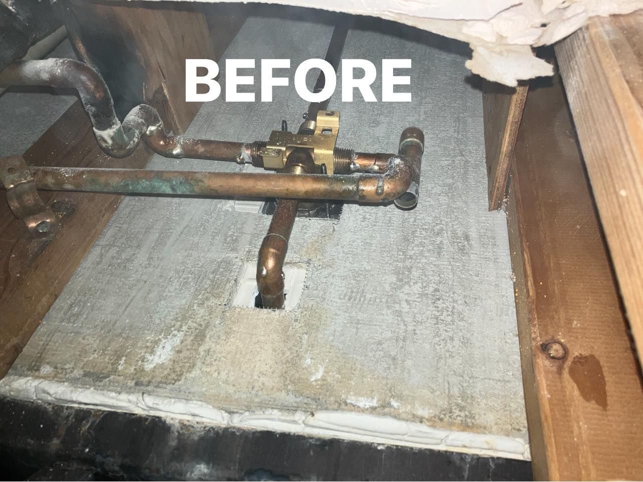 Before view of rusty pipe under a sink on a concrete floor