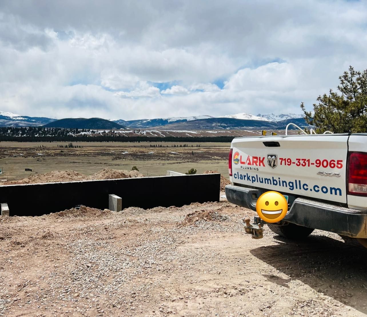 Construction trailer beside a gravel lot with mountains under a cloudy sky