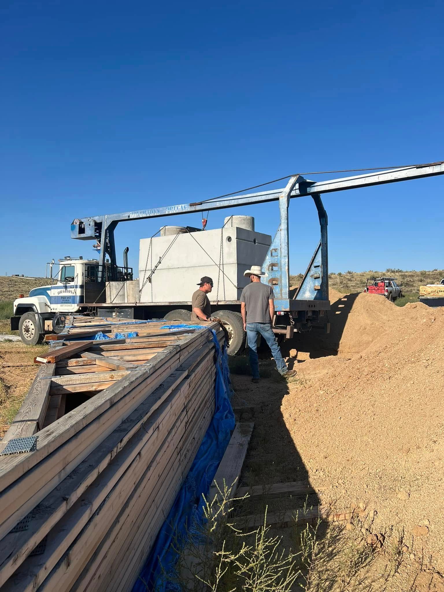Worker at a farm machine unloading wood chips beside a conveyor under a clear blue sky