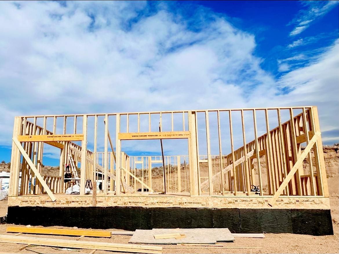 Wood-framed house under construction against a blue, cloudy sky