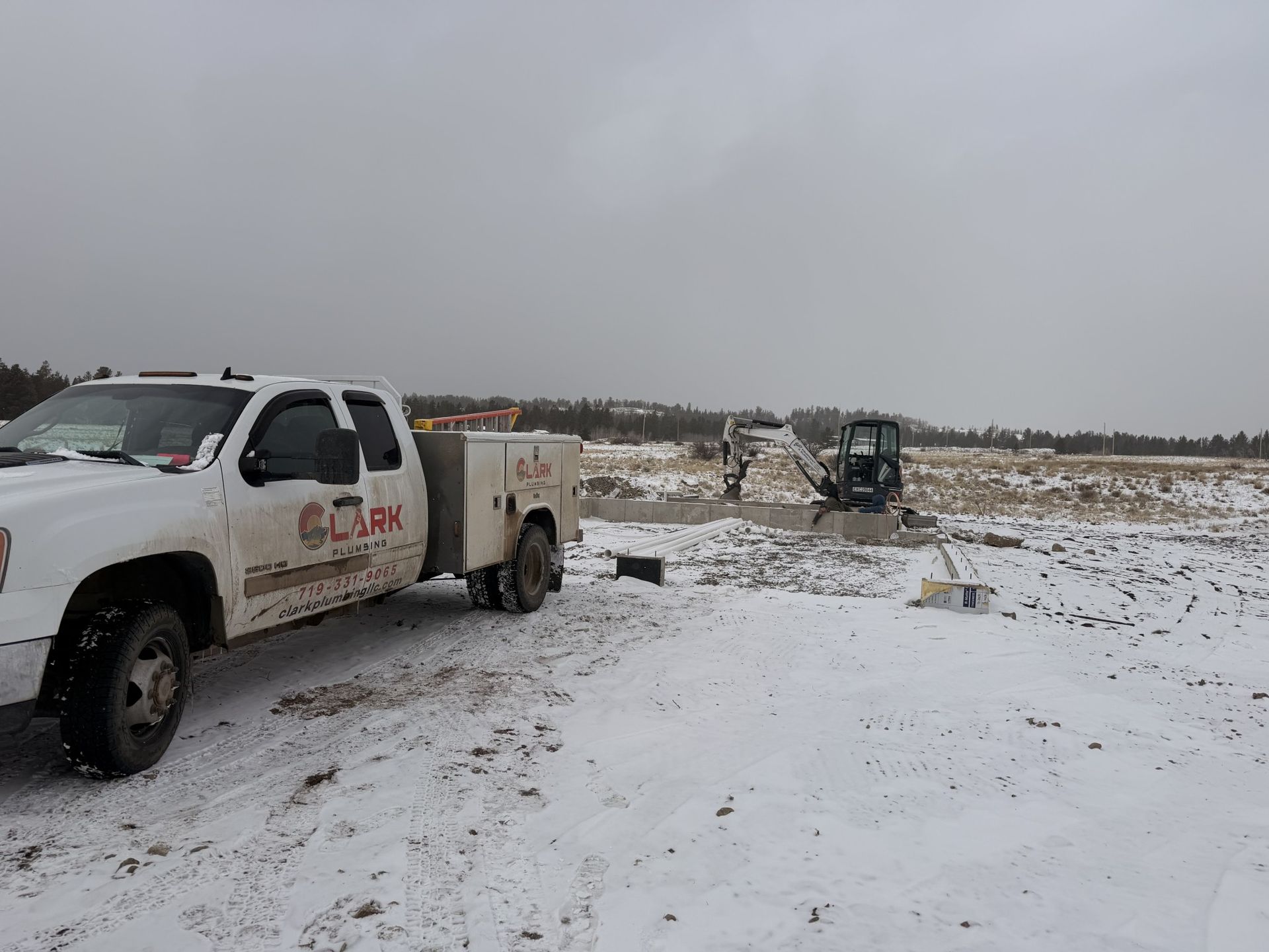 White pickup truck and off-road vehicle in a snowy field under a gray sky
