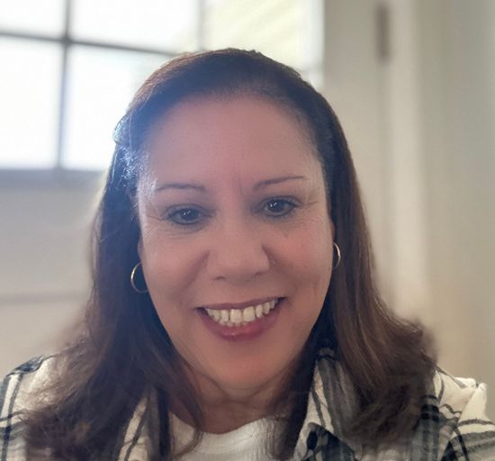 A woman in a plaid shirt is smiling for the camera.