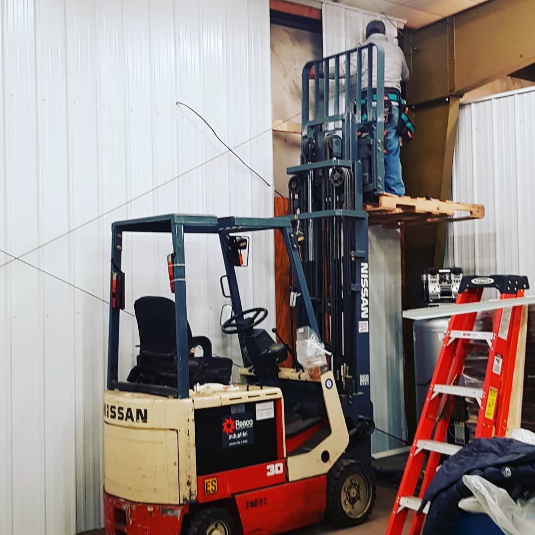 Red Nissan forklift in a warehouse beside a red ladder and stacked equipment