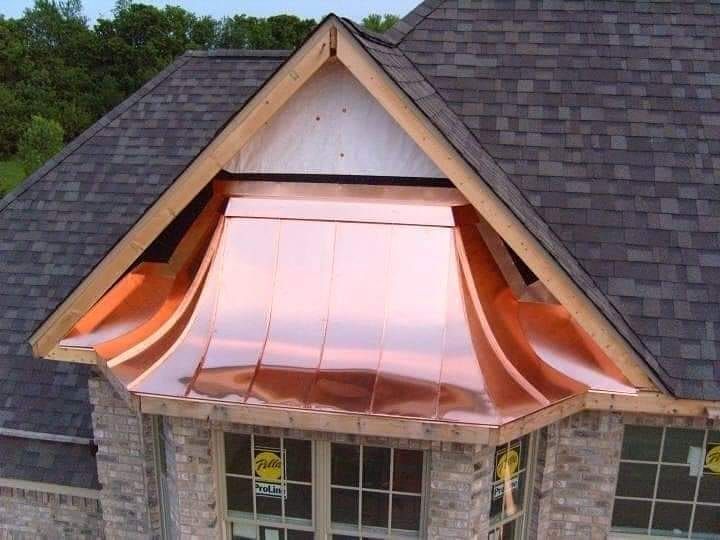 Copper awning over a dormer window on a shingled roof