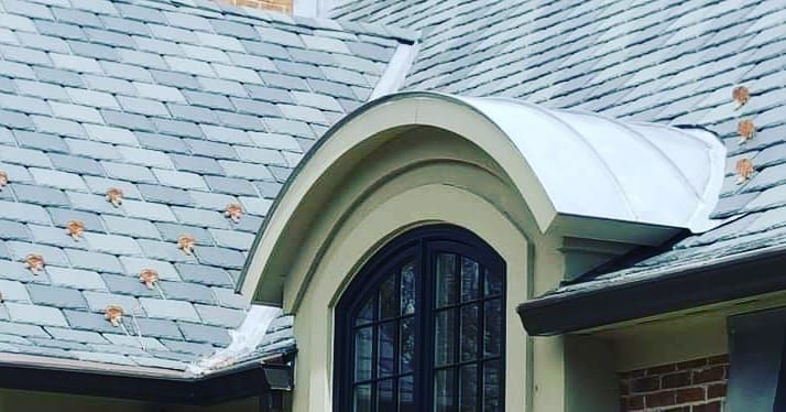 Arched dormer window with white trim on a gray shingled roof