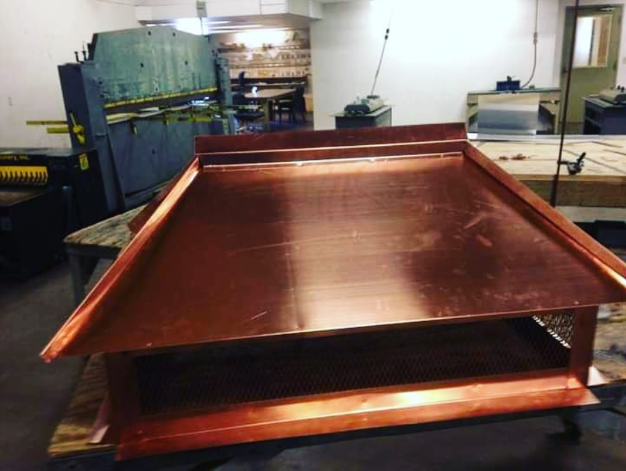 Copper-colored metal tray in an industrial workshop with machinery in the background
