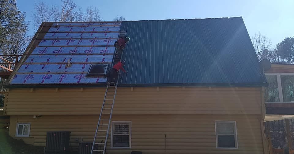 House with solar panels on one side of the roof, a ladder leaning against it, and a person working near the top
