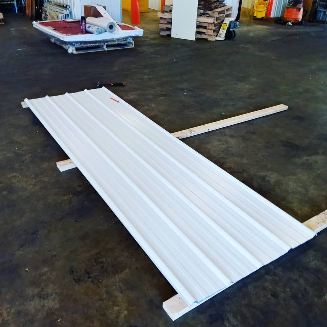 White corrugated metal panel on wooden supports in a warehouse or workshop setting