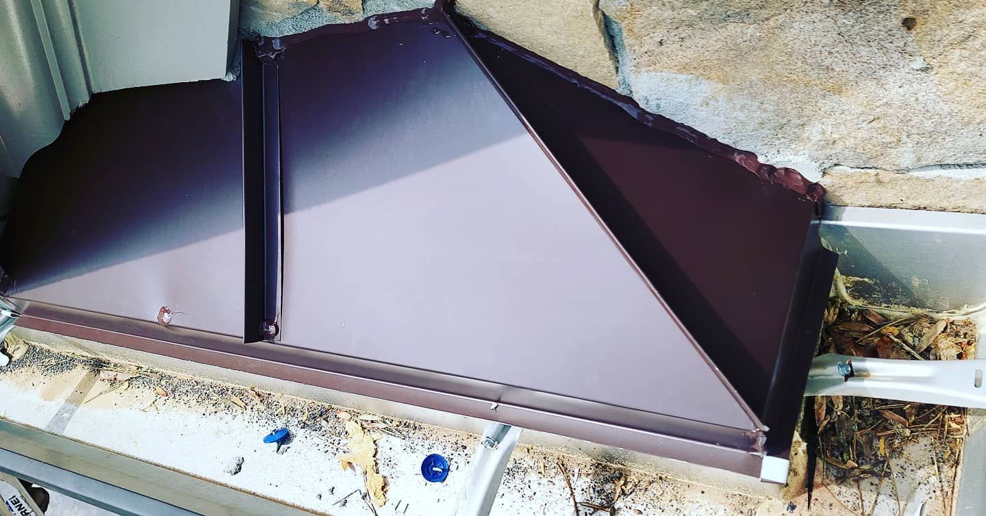 Purple geometric metal structure on a concrete surface, likely a folded shade or panel.