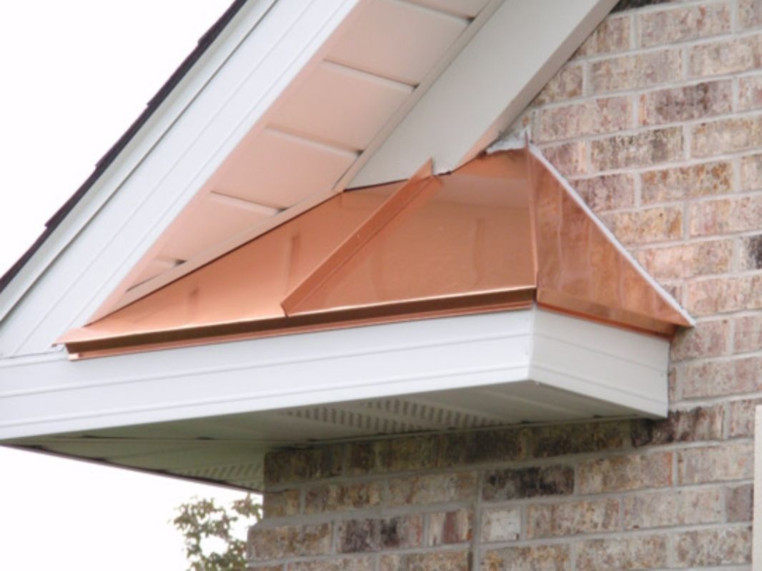 Copper-colored roof vent on a house exterior beneath the eaves