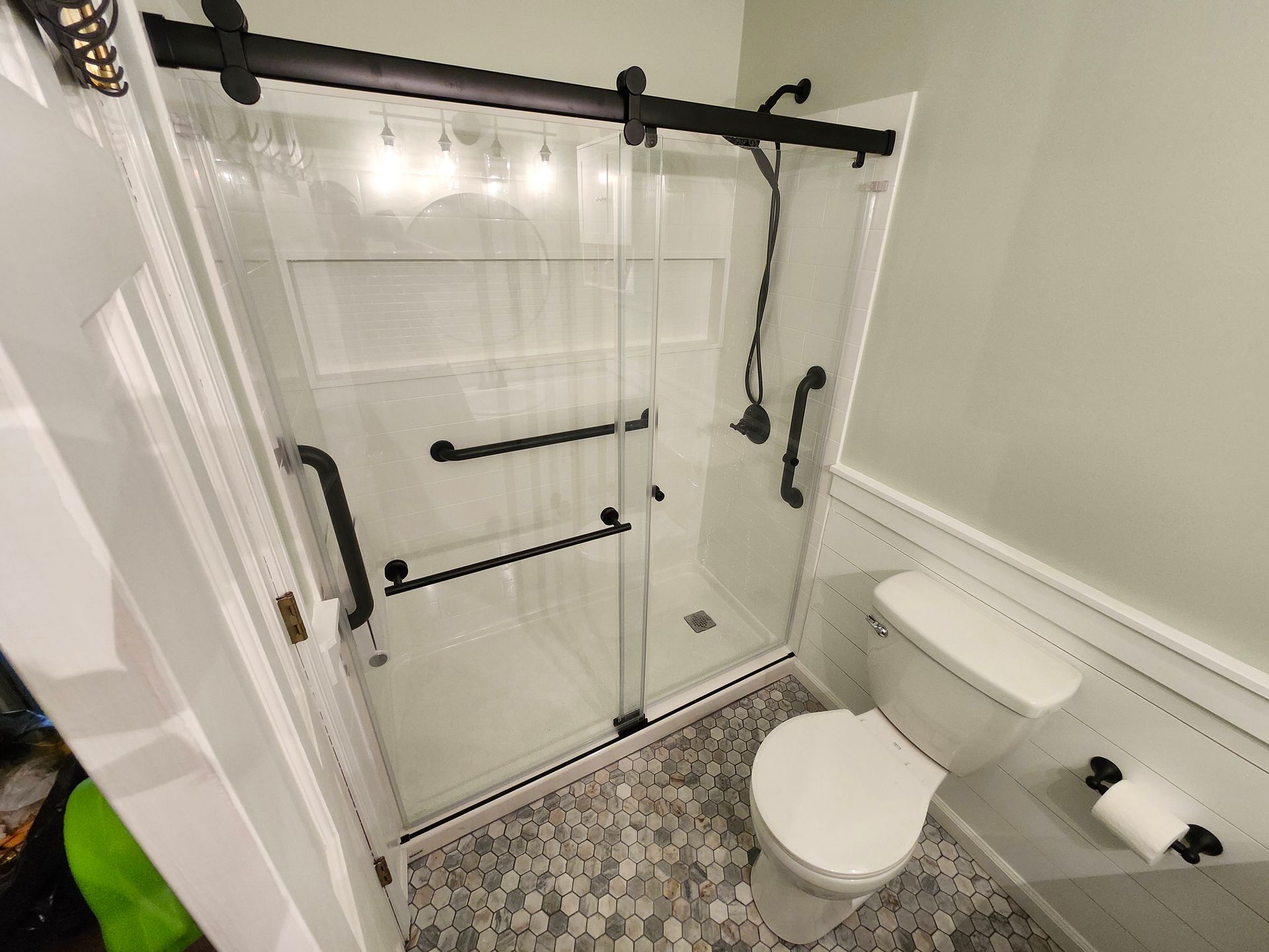 Small bathroom with walk-in shower, toilet, and grab bars on the walls.