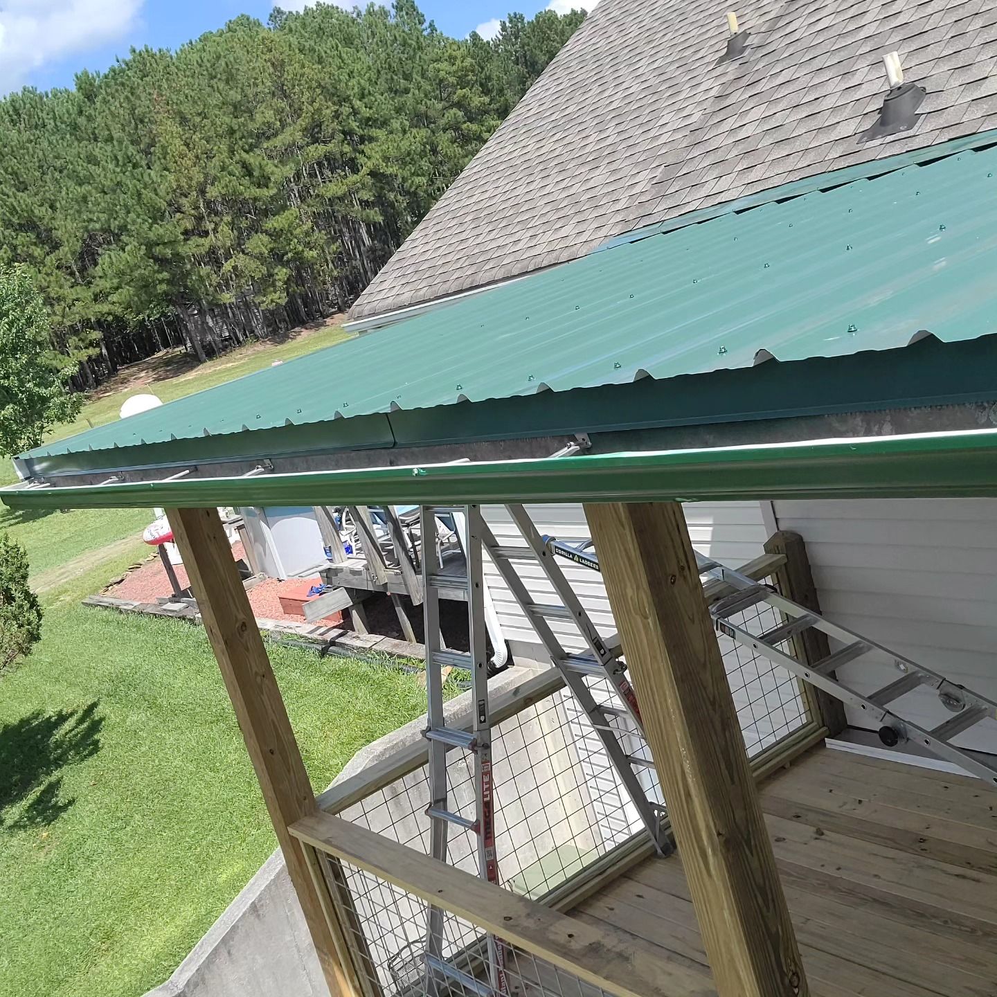 Green roof edge with ladders and wooden supports beside a building under blue sky