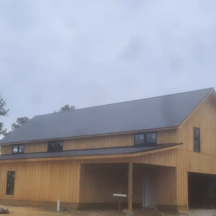 Modern wooden house with a metal roof and covered porch under a cloudy sky