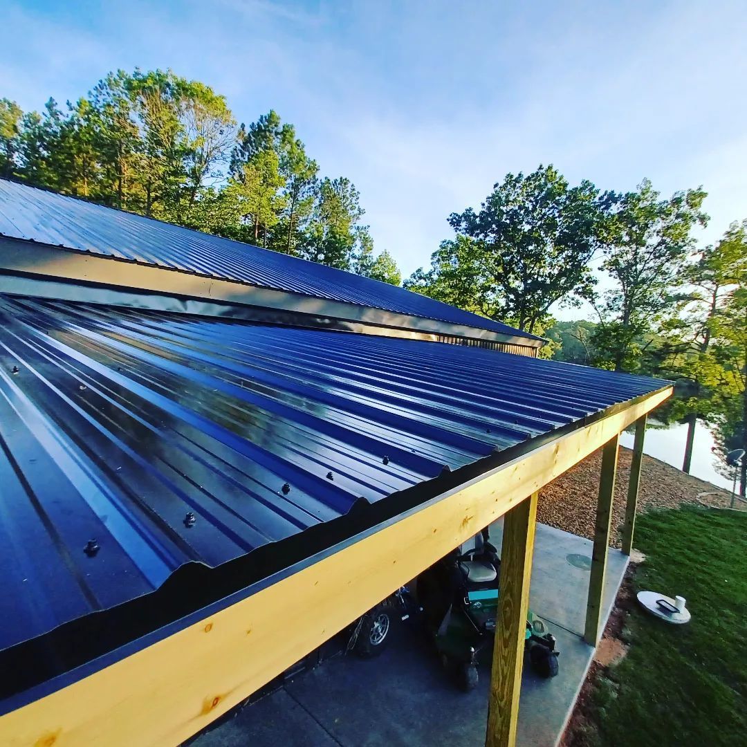 Blue metal roof under construction with exposed wooden beams and trees in the background