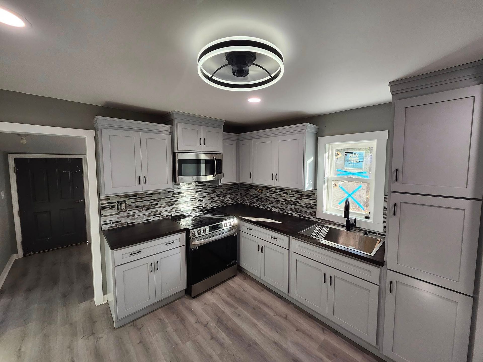 Modern gray kitchen with white cabinets, black countertops, and a circular ceiling light