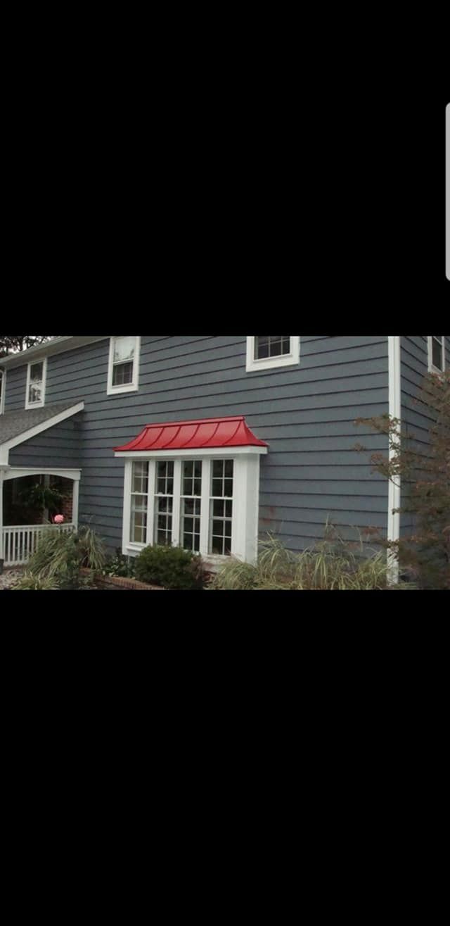 Blue house exterior with white-trimmed windows and a small red awning over the front door.