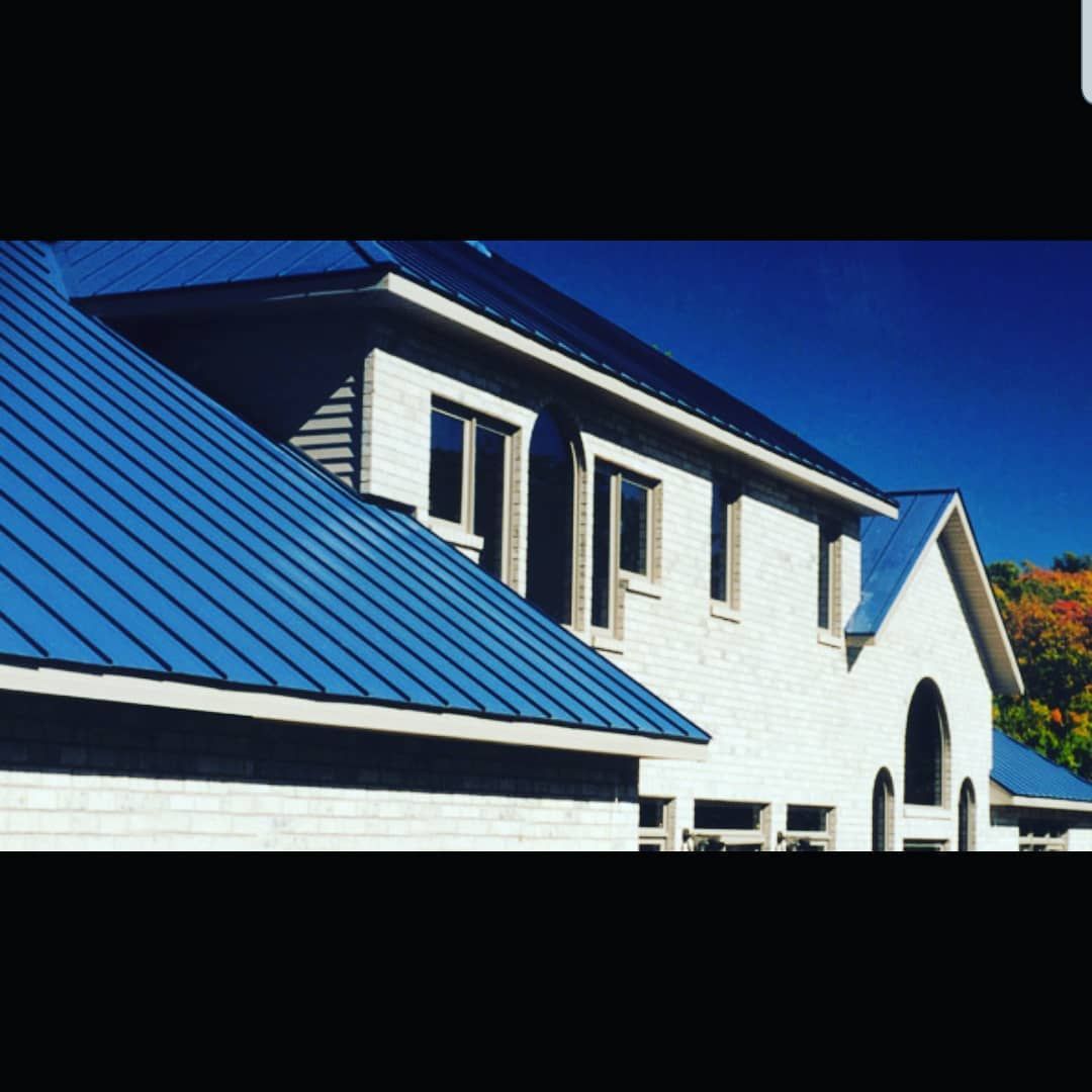 White building with blue metal roof under a clear blue sky