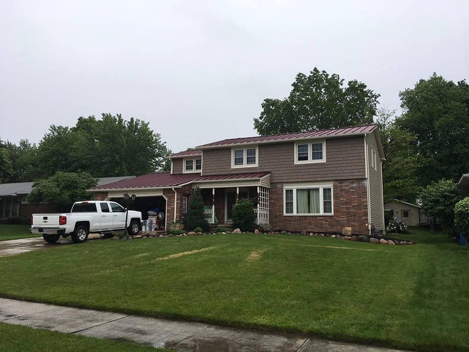 Suburban two-story brick house with white truck parked in driveway and a large green lawn.