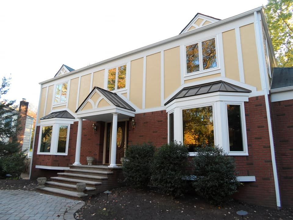 Brick-and-beige two-story house with white trim, front steps, and small covered porches