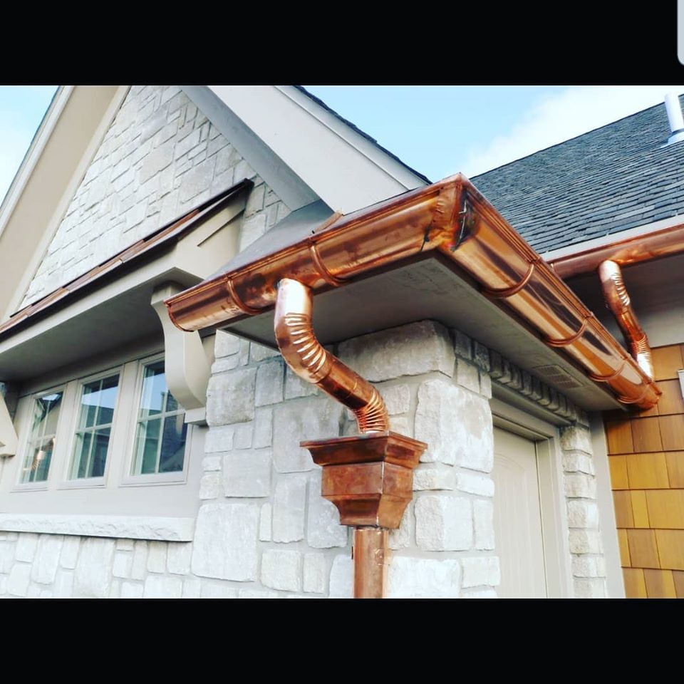 Copper rain gutters and downspout on a stone house exterior