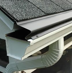 Damaged roof gutter with bent metal flashing and a downspout attached under shingles
