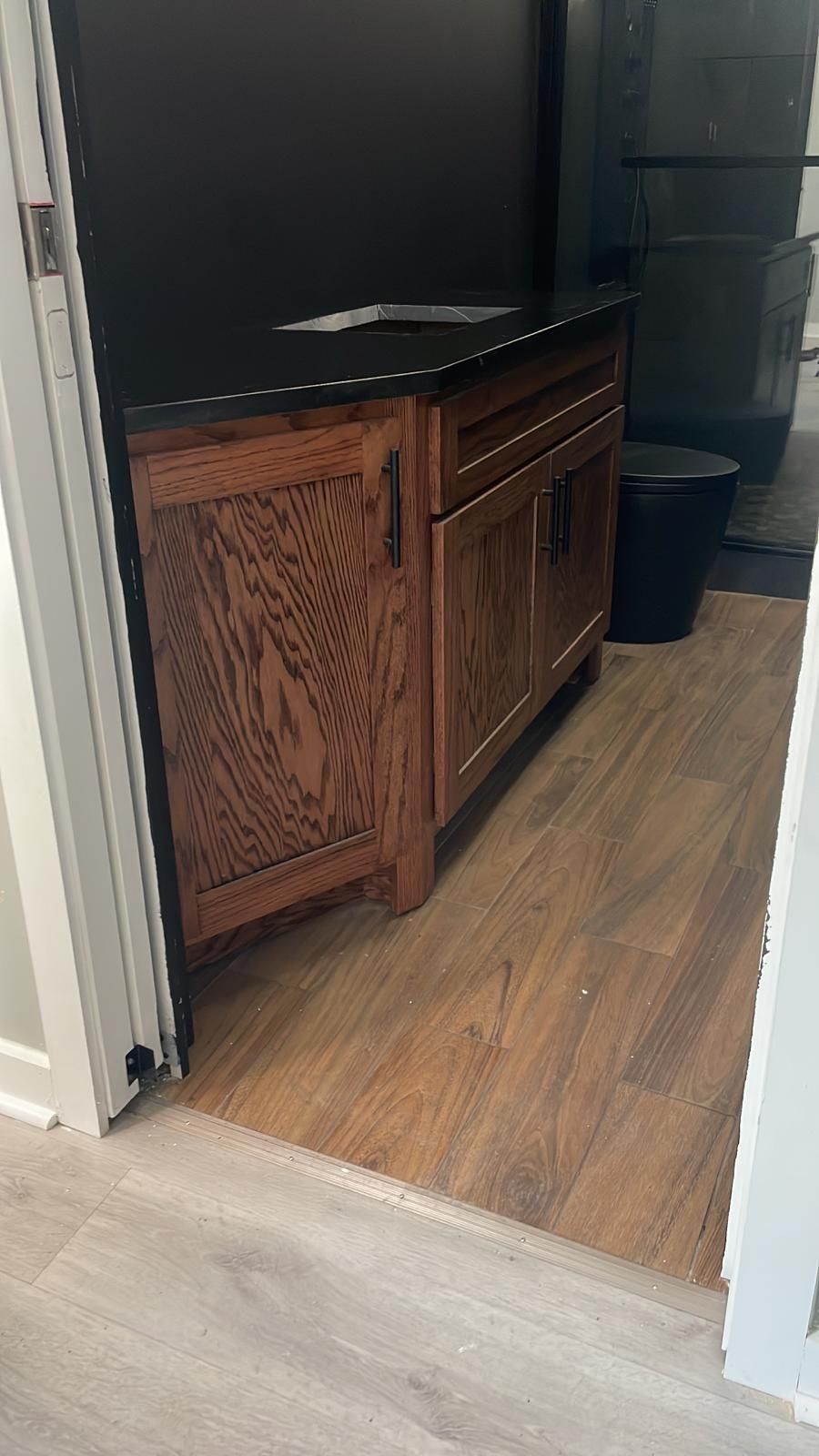 Wooden TV stand in a doorway between rooms, with a black TV on top and hardwood flooring.