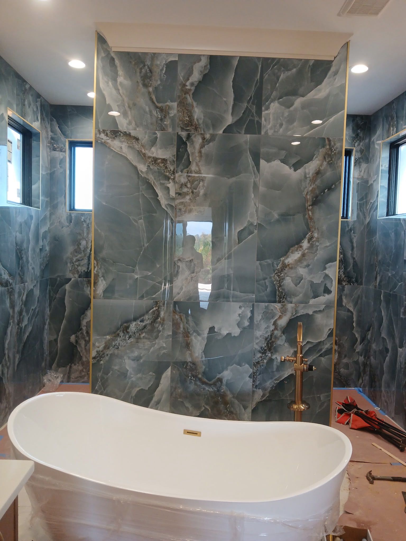 Modern bathroom with a freestanding white tub and a large gray marble shower wall.