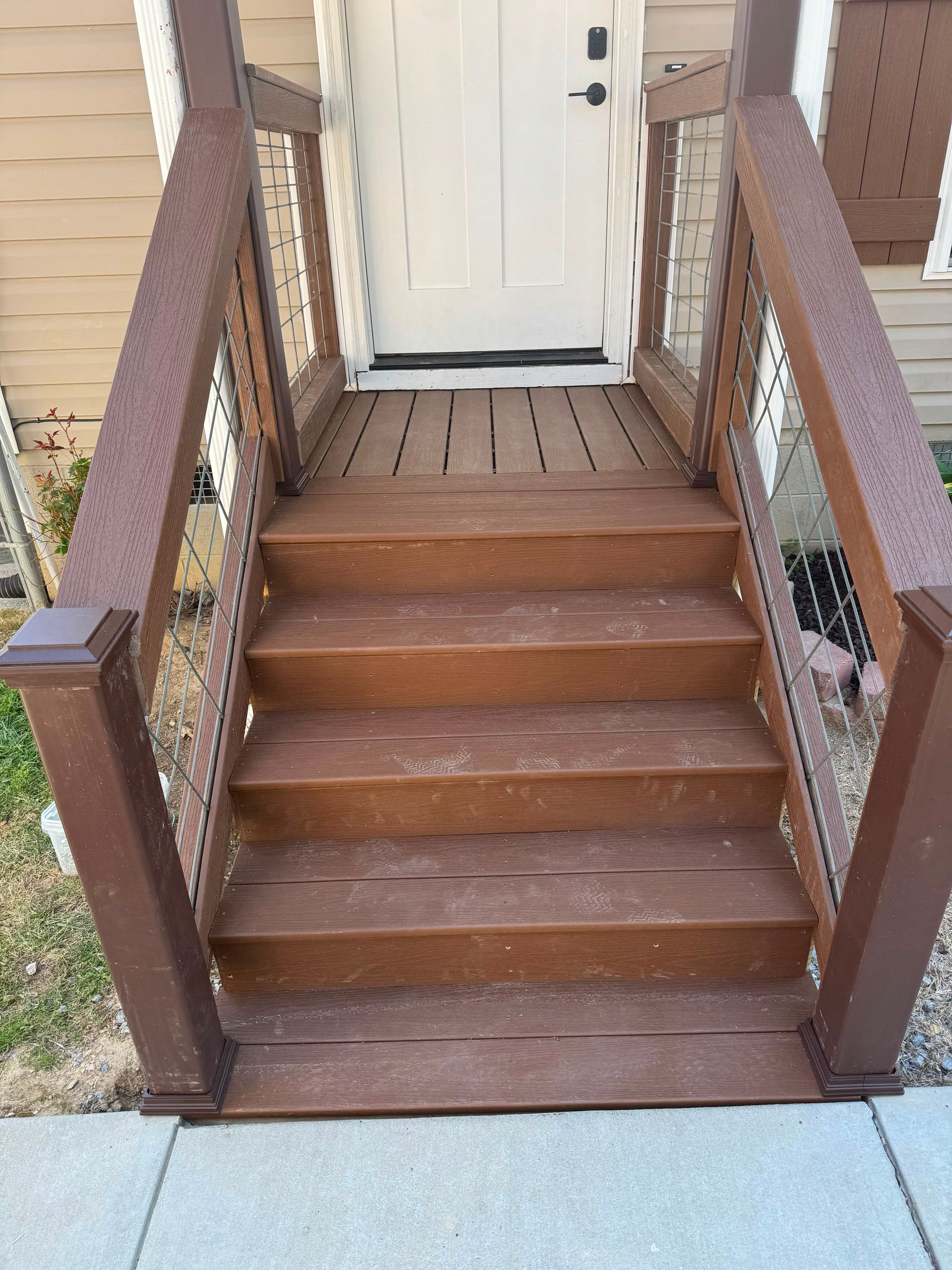 Wooden front steps with railings leading up to a white door