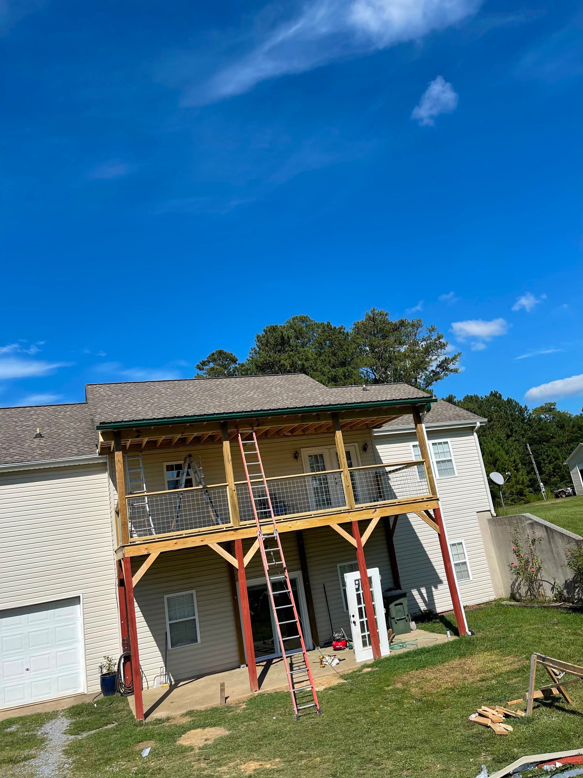 Two-story house with a covered porch, red support posts, and a blue sky above