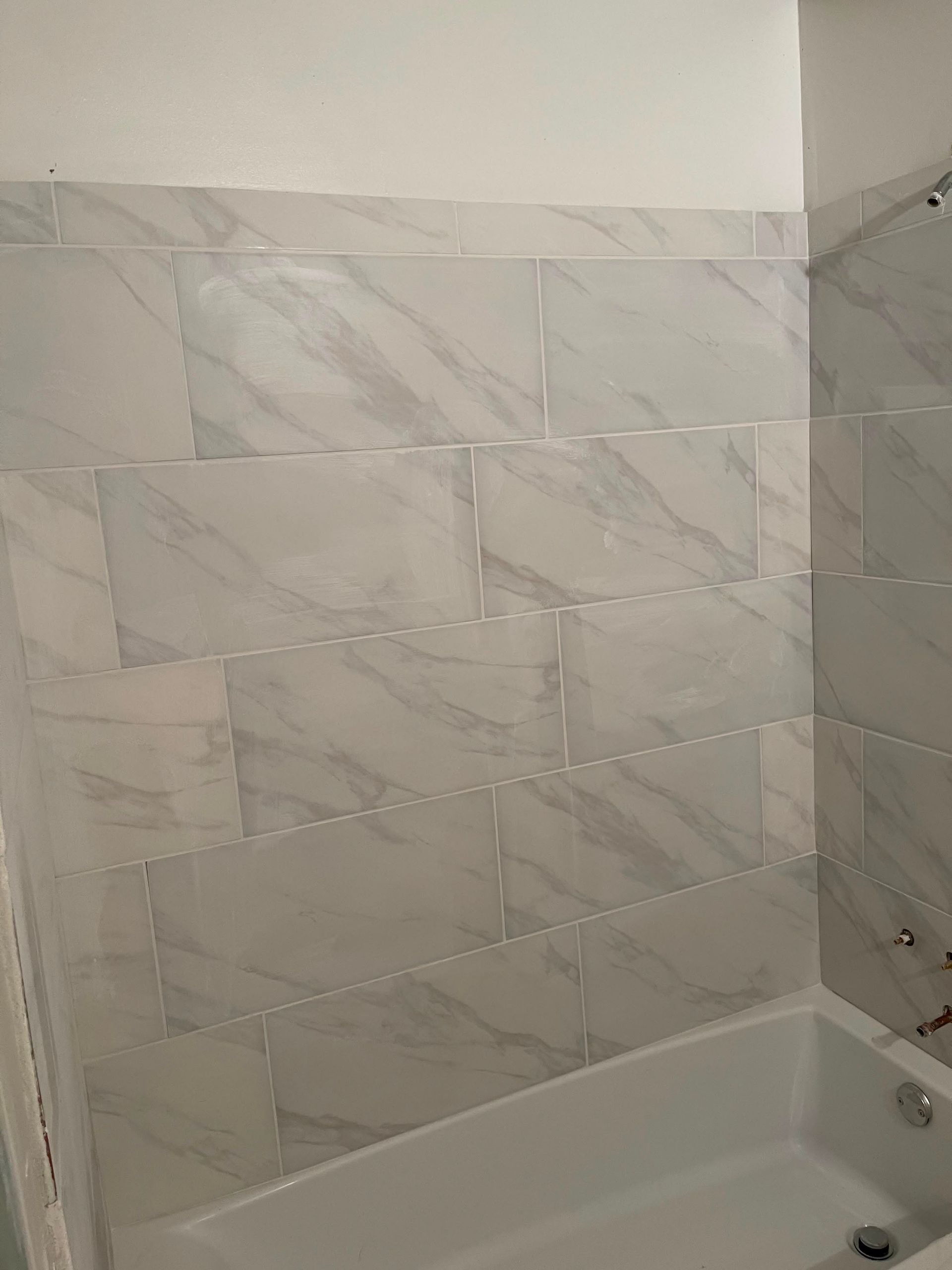 Empty bathtub with marble-look tile surround in a bathroom corner