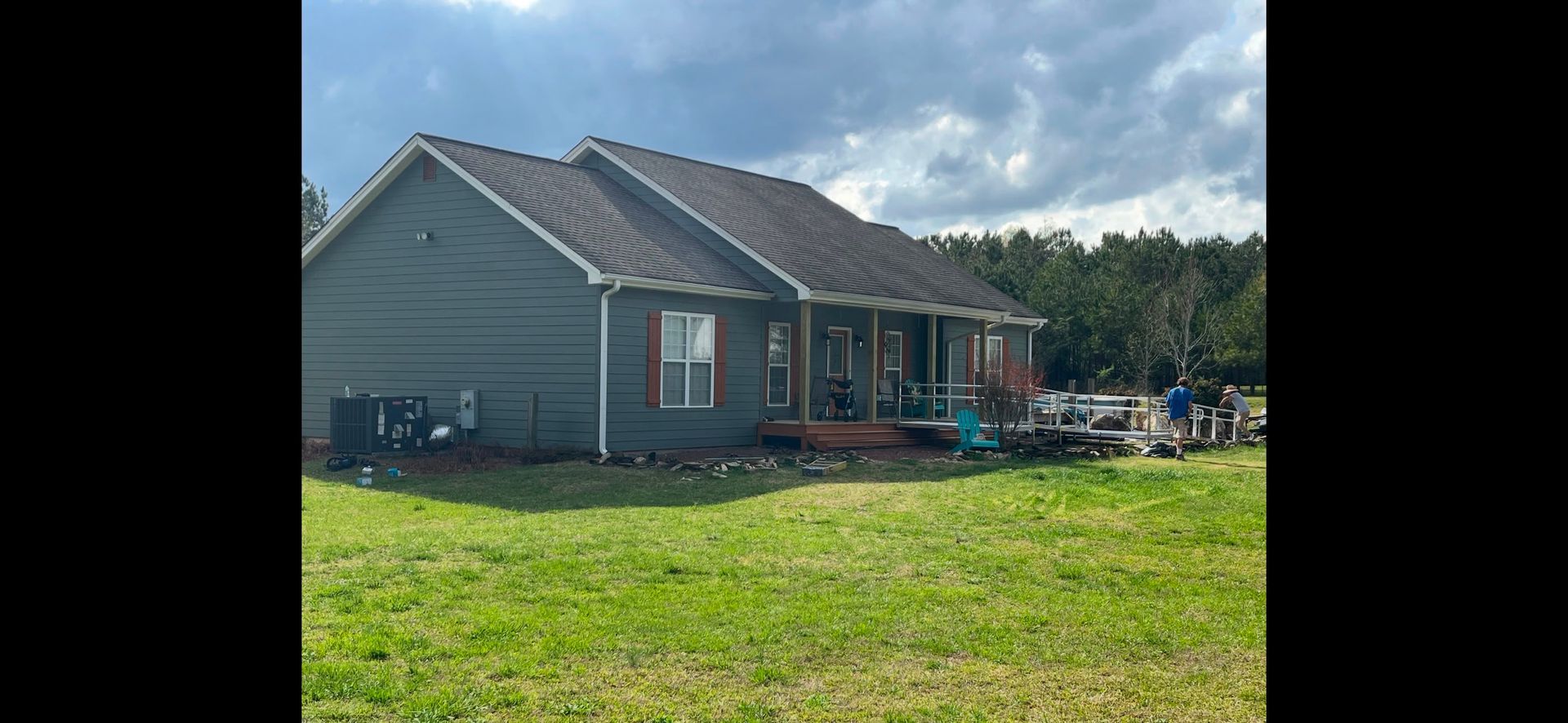 Gray house with a screened porch in a grassy yard under a cloudy sky